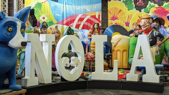 A collection of Mardi Gras floats in a warehouse setting