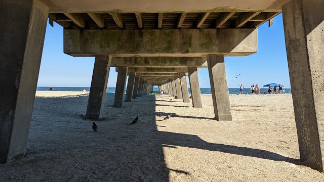 Beneath the Tybee Island beach pavilion, looking through the support beams out at the ocean.