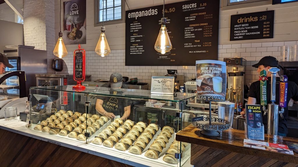 A glass display with many types of empanadas in it.